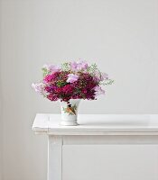 Bouquet of sweet william, sweet peas and shepherd's purse in vase on white table