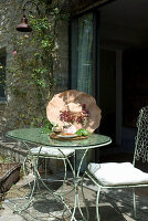 Metal patio table with decoration and stone façade in the background