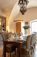 Gedeckter Esstisch mit Rattanstühlen in rustikalem Gewölberaum