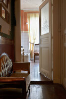 View through an open door to a bright bathroom with chair