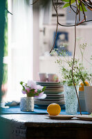 Lemon still life on a rustic wooden table with crockery, flowers and vases