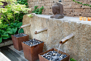 Wasserlauf aus Bambusröhren und Steinskulptur im Zen-Garten