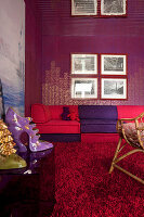 Red and purple couch in front of patterned wall with artwork