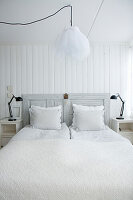 Hell gestaltetes Schlafzimmer mit Doppelbett und weißer Bettwäsche