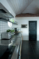 Modern kitchen with black floor tiles and black door that acts as a blackboard