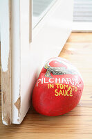 Painted stone as a doorstop with the inscription "Pilchards in Tomato Sauce"