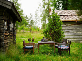 Seating area with wooden furniture in front of a rustic wooden hut