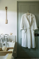 White bathrobe on green door in bathroom