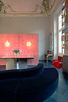 Velvet sofa and pink wall in historic living room with stucco ceiling