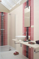 Bathroom with glass shower cubicle and washbasin, tiles in shades of pink, purple and white