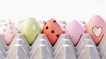 Fünf verschieden dekorierte Ostereier in Eierpalette