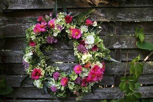 Summer wreath of hydrangeas, asters, sage and grasses hanging on wooden fence