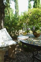 Weinglas auf antiker Steinbank mit Polstern und Buch auf gefliestem Tisch