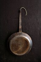 Vintage iron frying pan hanging on black wall
