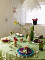 Table set with a green tablecloth in a white wood paneled dining room