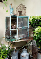 Vintage Gartendeko mit altem Schrank, Vogelkäfigen und Hortensien