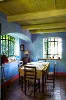 Rustic dining area in Mediterranean country house with blue marbled walls combined with antique lattice windows