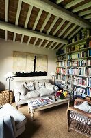 Comfortable living room with country-style seating area and bookcase below rustic wood-beamed ceiling