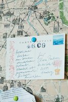 Printed and hand-written postcard on pin board with map as background