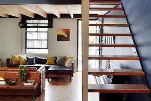 Living room with leather sofas, staircase in the foreground in front of a deep blue wall