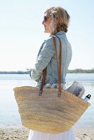 Blonde woman with woven picnic bag on beach