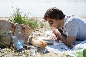 Man on a beach picnic reading a book