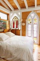 Bedroom with stained glass window and wooden beam ceiling; Taos; New Mexico; USA