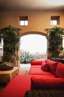 Zeitgenössisches Wohnzimmer mit rotem Sofa und bogenförmigen Durchgang zur Terrasse