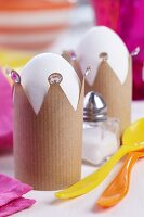 Crown-shaped eggcups made from brown paper decorated with rhinestones