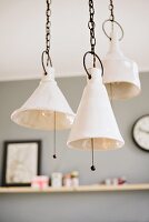 Artistic, ceramic pendant lamps hanging from chains with pull switches