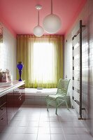 Colourful modern bathroom with pink ceiling, yellow perforated curtain, mint green chair and blue glass vase