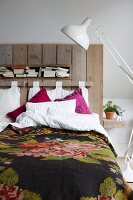 White retro standard lamp next to bed with vintage-style bedspread and headboard made from reclaimed boards