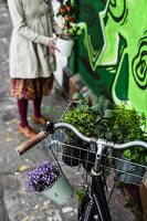 Mit Pflanzen dekoriertes Fahrrad vor mit Graffiti besprühter Wand