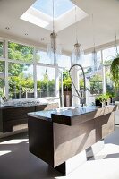 Elegant kitchen island in light-flooded interior with pendant lamps above counter and skylight