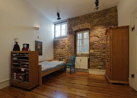 Spartan child's bedroom with rustic stone wall and old wooden floor
