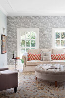 Living room with light grey patterned wallpaper and Chesterfield stool