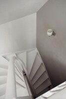 Blick von Oben in puristisches Treppenhaus mit hellgrauen Wänden & weisser Wendeltreppe