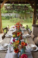 Rustic wooden table set with autumn flowers on roofed terrace