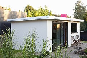 White summer house and terrace in summery garden