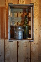 Old milk churn and swing-top bottle decorating fruit crate hung on wall of wooden house