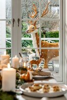 Fake reindeer outside French windows seen over set table