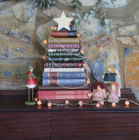 Stilisierter Weihnachtsbaum aus Bücherstapel, dekoriert mit Lichterkette