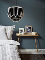 Black and white lantern-style lamp above bed with striped bed linen and bedside table