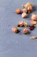 Getrocknete Rosenknospen und Kamillenblüten auf grau strukturierter Oberfläche