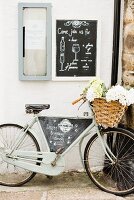 A bicycle with a basket full of flowers and advertising sign for restaurant