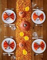 Gedeckter Tisch für Halloween dekoriert mit Kürbissen, Kerzen und Candy Corn (Aufsicht)
