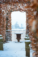 Blick auf Laubengang, verschneiten Garten und Steinvase