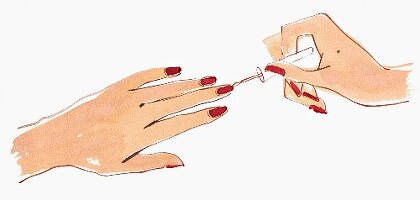 Nahaufnahme der Hände einer Frau die roten Nagellack aufträgt