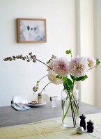 Cut flowers in glass vase on table next to salt and pepper pots