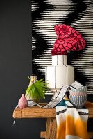 Still-life arrangement of vases and bowls on wooden table against black and white artwork on wall